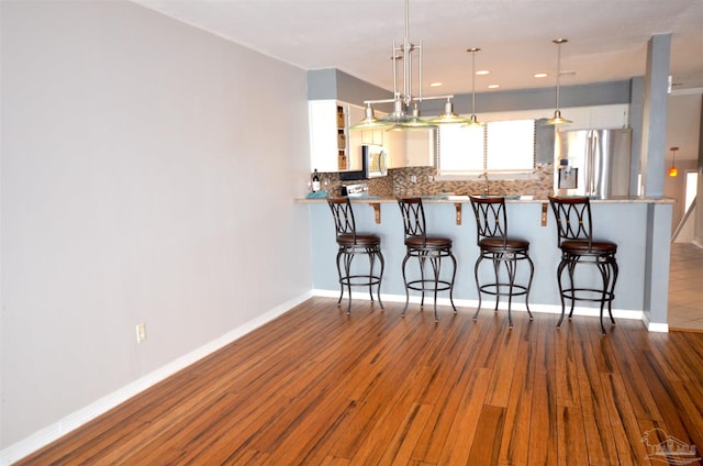 kitchen featuring stainless steel appliances, dark wood-type flooring, a peninsula, and a kitchen breakfast bar