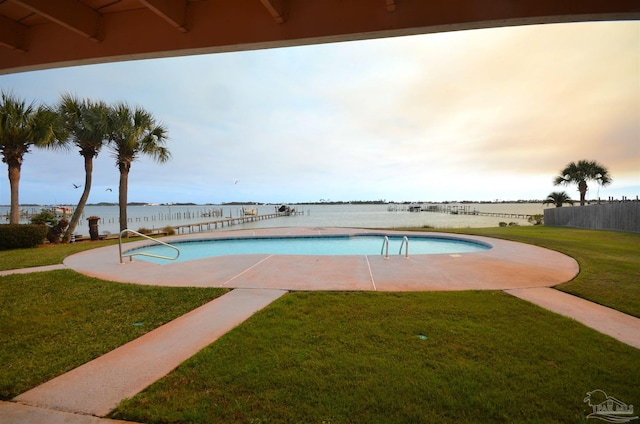 outdoor pool with a lawn, a patio area, and a water view