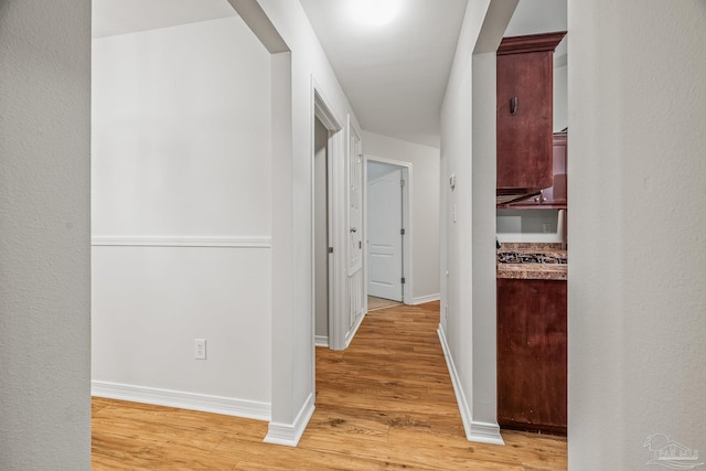 hall featuring light wood-type flooring and baseboards