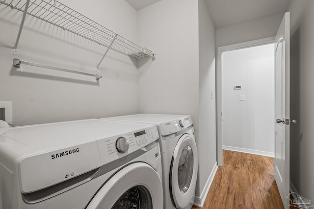 laundry area with light wood-style floors, laundry area, baseboards, and washing machine and clothes dryer