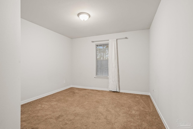 empty room featuring carpet and baseboards