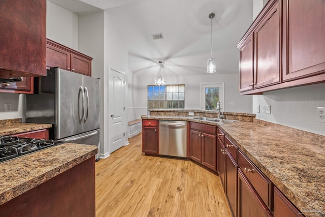 kitchen featuring reddish brown cabinets, visible vents, light wood-style flooring, stainless steel appliances, and a sink