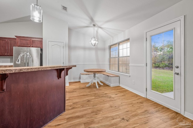 dining area featuring visible vents, baseboards, vaulted ceiling, light wood finished floors, and an inviting chandelier