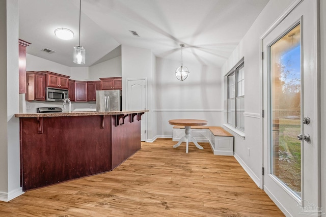 kitchen featuring visible vents, a breakfast bar area, appliances with stainless steel finishes, and dark brown cabinets