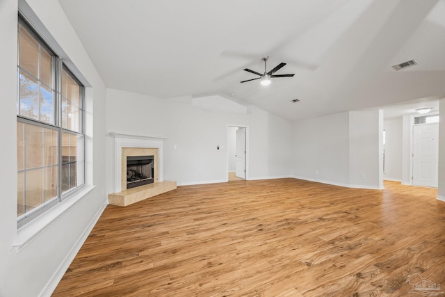 unfurnished living room with light wood-style flooring, a fireplace, visible vents, a ceiling fan, and vaulted ceiling