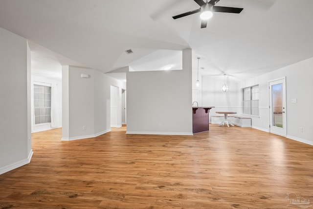 unfurnished living room with light wood-style flooring, visible vents, baseboards, vaulted ceiling, and a ceiling fan