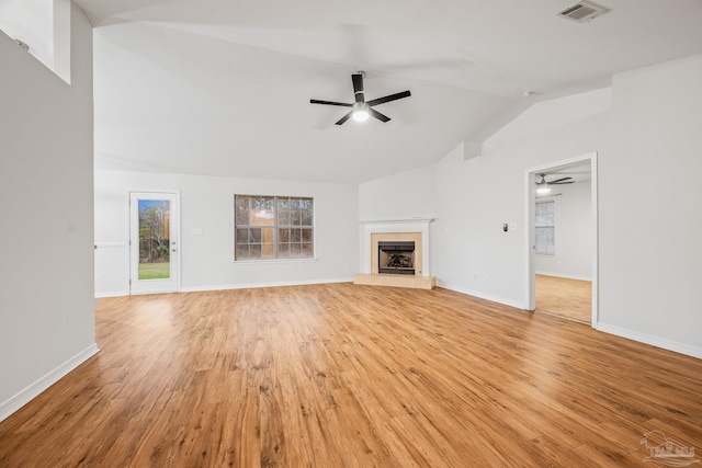 unfurnished living room with visible vents, a tiled fireplace, ceiling fan, light wood-style flooring, and vaulted ceiling