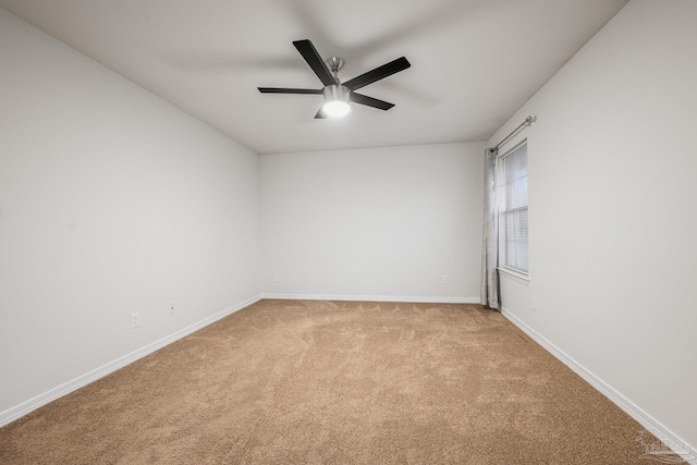 spare room featuring a ceiling fan, light carpet, and baseboards