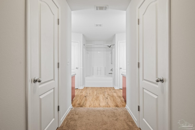 hall with light carpet, baseboards, and visible vents