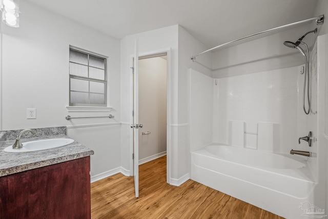 bathroom featuring vanity, wood finished floors, bathing tub / shower combination, and baseboards