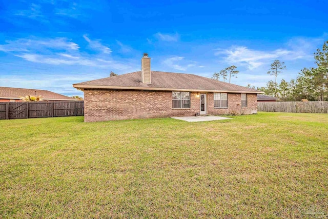 rear view of property with a fenced backyard, brick siding, a yard, a chimney, and a patio area