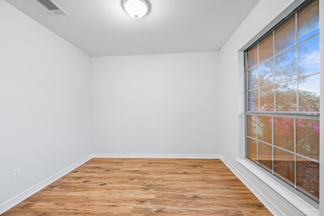 empty room featuring light wood finished floors, visible vents, and baseboards