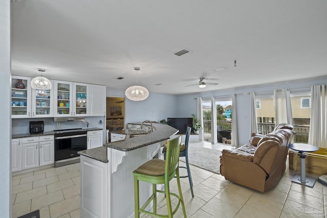 kitchen with sink, a breakfast bar area, white cabinetry, hanging light fixtures, and electric range oven