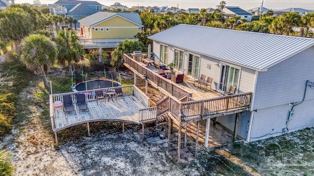 rear view of property featuring a wooden deck and a trampoline