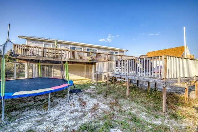 back of house with a wooden deck and a trampoline