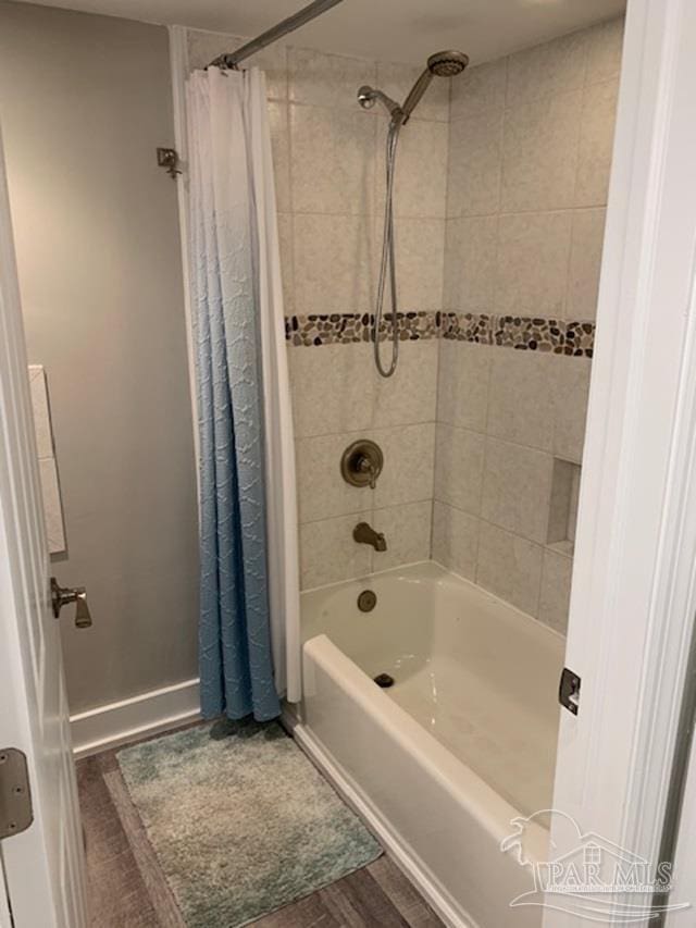 bathroom with hardwood / wood-style floors and shower / tub combo with curtain