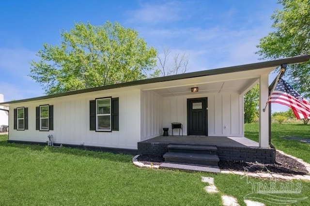 rear view of property with a yard, covered porch, and board and batten siding