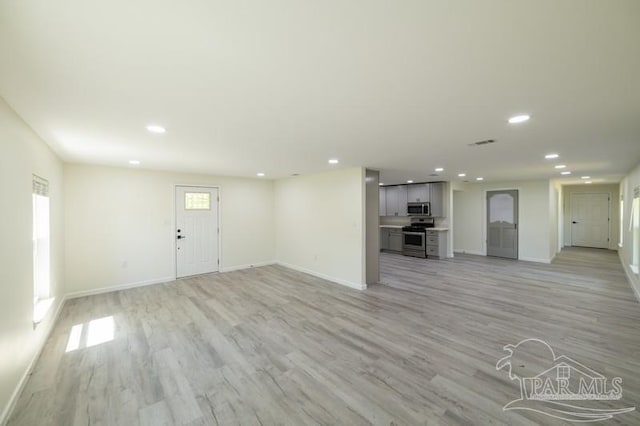unfurnished living room featuring light wood finished floors, baseboards, visible vents, and recessed lighting