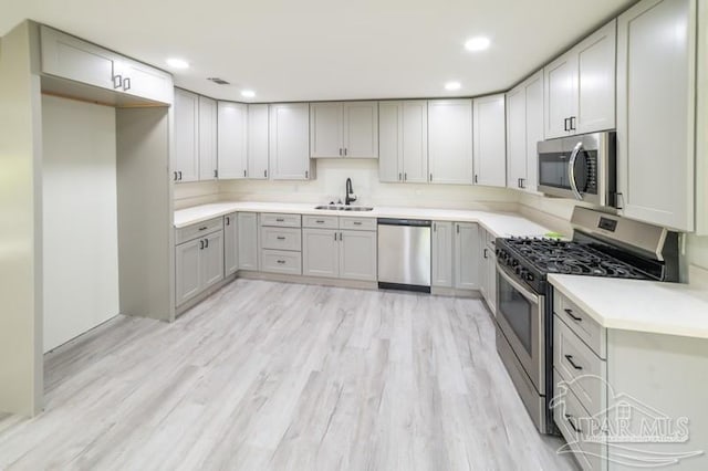 kitchen with recessed lighting, light wood-style flooring, light countertops, appliances with stainless steel finishes, and a sink
