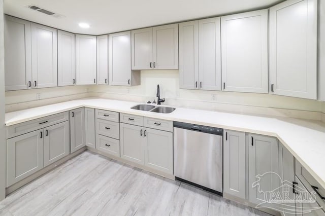 kitchen featuring visible vents, gray cabinets, dishwasher, a sink, and light countertops
