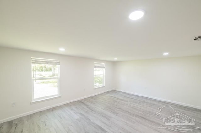 spare room with light wood-type flooring, a healthy amount of sunlight, and baseboards