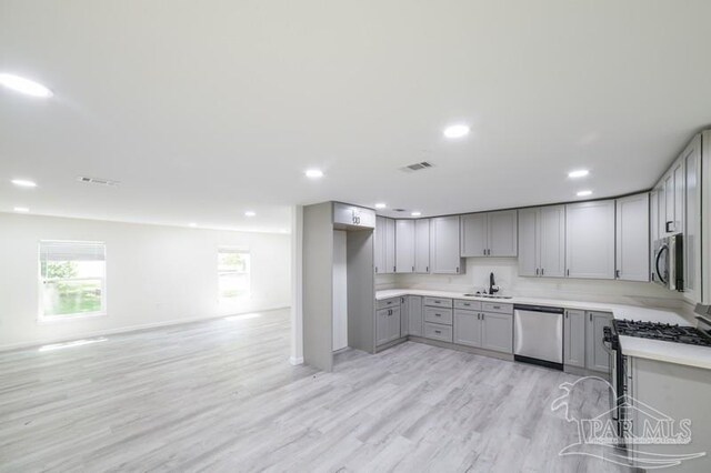 kitchen featuring light wood-style floors, visible vents, gray cabinets, appliances with stainless steel finishes, and a sink