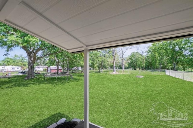 view of yard with a trampoline and fence