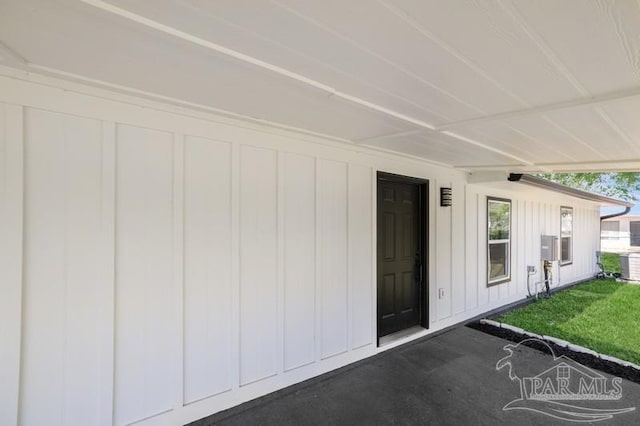doorway to property featuring board and batten siding and a yard