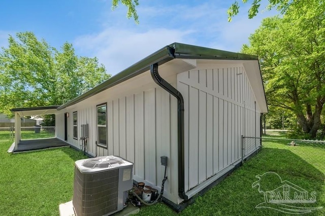 view of property exterior with board and batten siding, central AC unit, and a lawn