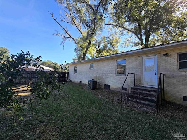 back of house with cooling unit and a lawn