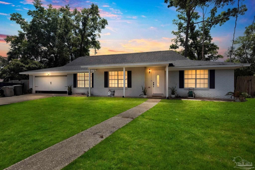 ranch-style house featuring a garage and a yard