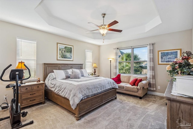 bedroom featuring light carpet, ceiling fan, and a raised ceiling