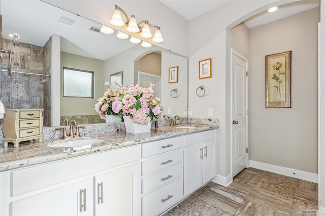 bathroom with tiled shower and vanity