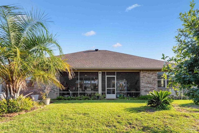 back of property featuring a sunroom and a lawn