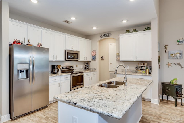 kitchen featuring sink, light hardwood / wood-style floors, white cabinetry, appliances with stainless steel finishes, and a center island with sink