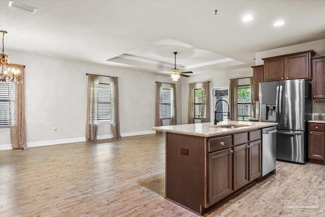 6372 Ladera Trl, Pace, FL 32571 - kitchen featuring stainless steel appliances, a sink, light wood-type flooring, a tray ceiling, and a kitchen island with sink