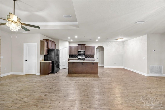 6372 Ladera Trl, Pace, FL 32571 - kitchen with stainless steel microwave, open floor plan, black fridge, ceiling fan, and arched walkways
