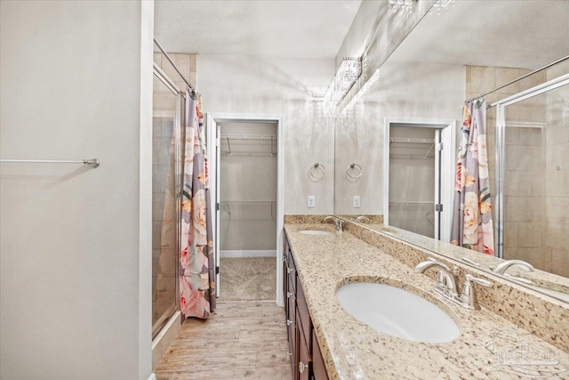 6372 Ladera Trl, Pace, FL 32571 - bathroom featuring a shower stall, a spacious closet, double vanity, wood finished floors, and baseboards