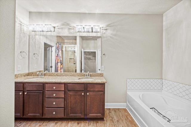 6372 Ladera Trl, Pace, FL 32571 - bathroom with wood finished floors, a shower stall, a garden tub, double vanity, and baseboards