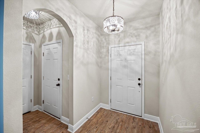 6372 Ladera Trl, Pace, FL 32571 - foyer entrance featuring wood finished floors, arched walkways, a chandelier, and baseboards