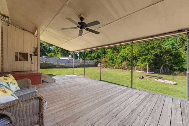 wooden terrace featuring a ceiling fan, fence, and a lawn