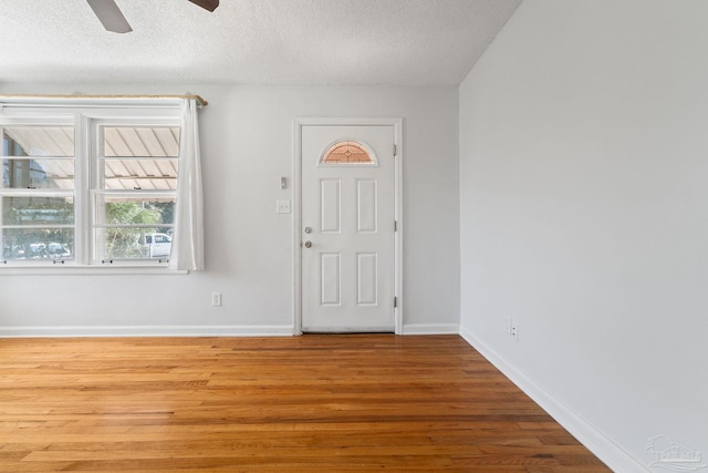 entryway featuring a ceiling fan, a textured ceiling, baseboards, and wood finished floors