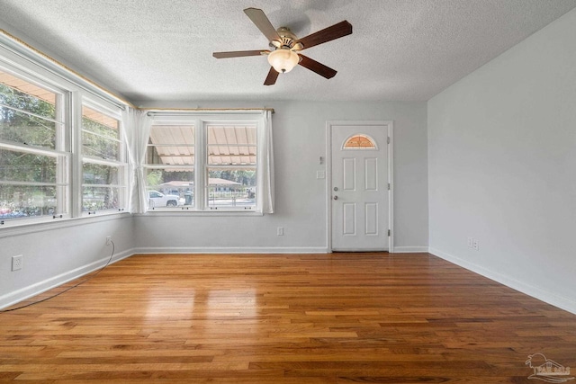 foyer featuring a ceiling fan, a textured ceiling, baseboards, and wood finished floors