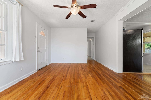 interior space with visible vents, a textured ceiling, baseboards, and wood finished floors