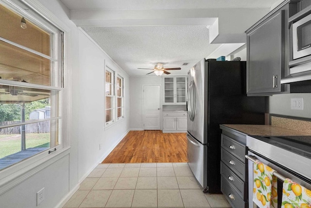 kitchen featuring ceiling fan, light tile patterned floors, a textured ceiling, and appliances with stainless steel finishes