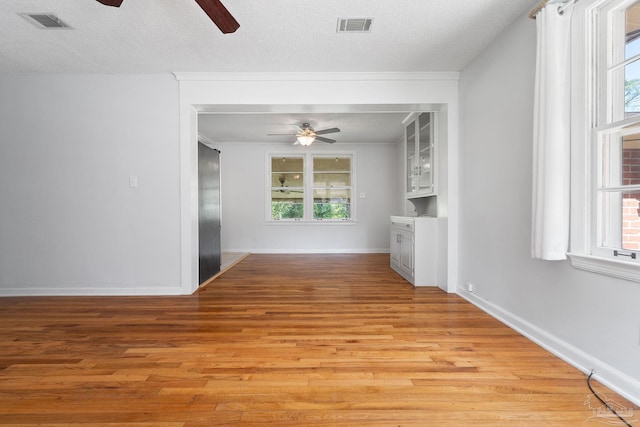 interior space featuring light wood-type flooring, visible vents, and a textured ceiling