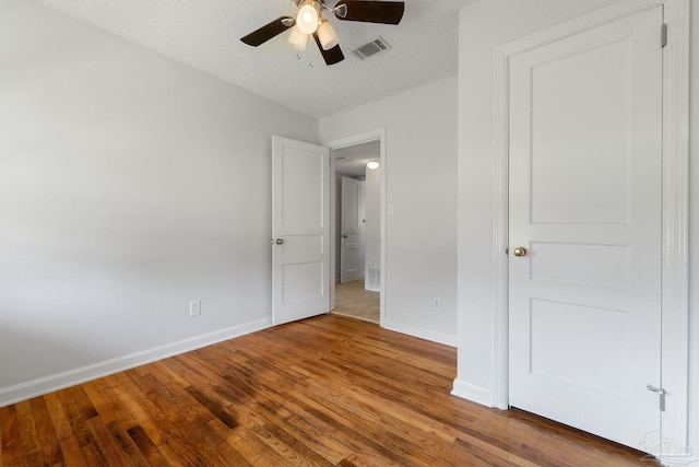 unfurnished bedroom featuring ceiling fan, wood-type flooring, and a textured ceiling