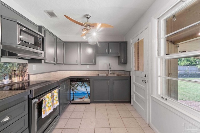 kitchen featuring gray cabinetry, stainless steel appliances, a sink, visible vents, and range hood