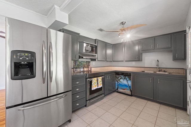 kitchen with dark countertops, gray cabinets, appliances with stainless steel finishes, a sink, and ceiling fan