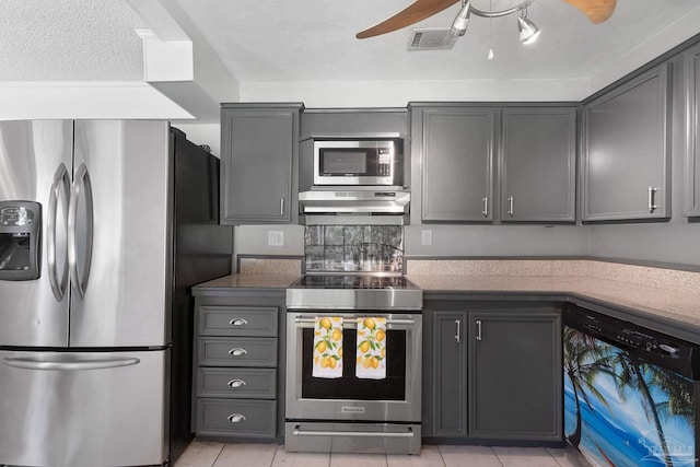 kitchen with under cabinet range hood, stainless steel appliances, a ceiling fan, visible vents, and dark countertops